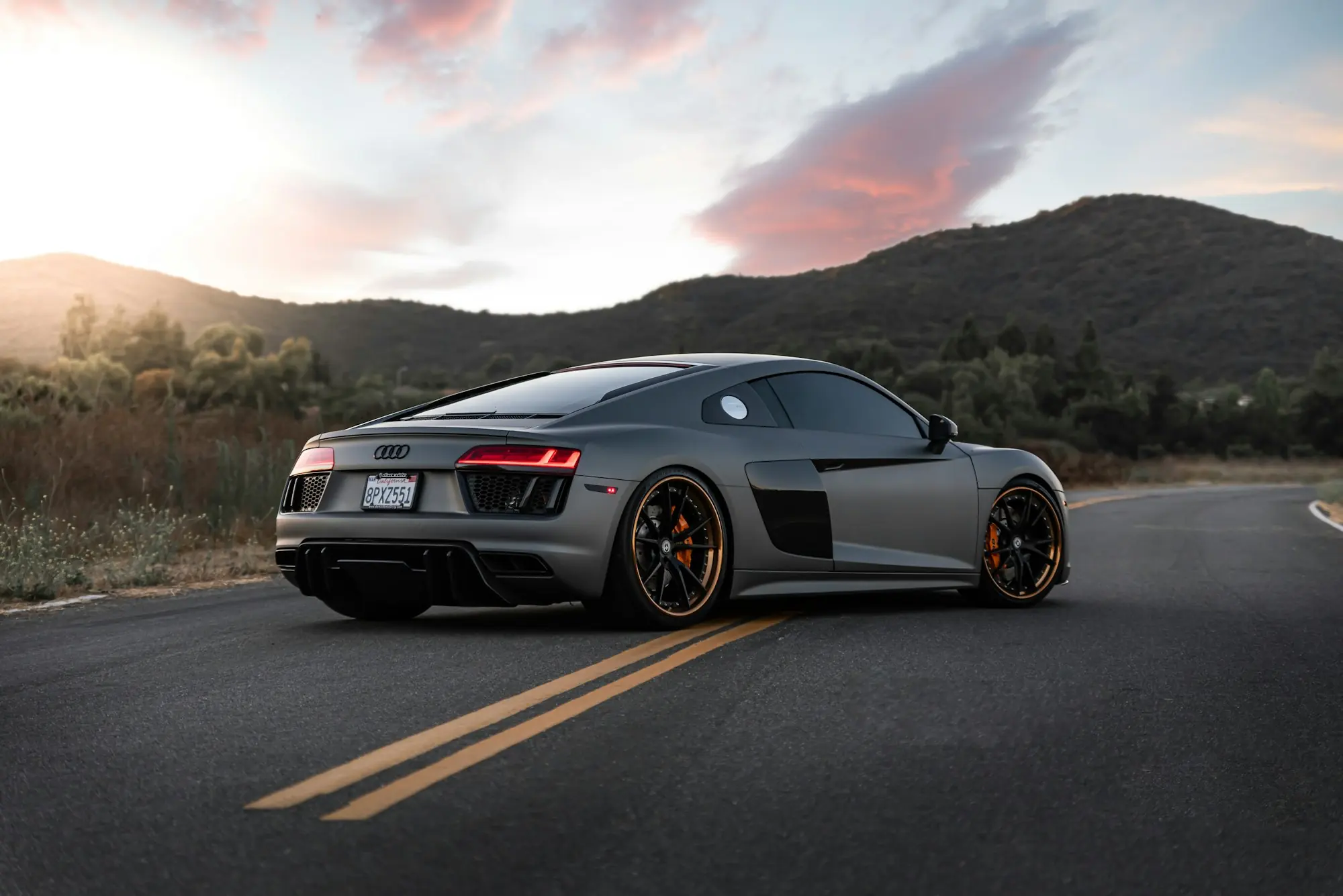 Audi R8 grigia su una strada di montagna al tramonto